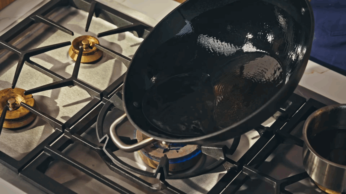 A wok coated in oil over a stovetop.