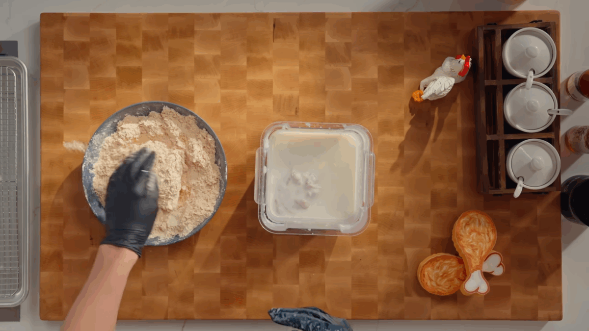 Chicken being breaded in wet and dry mixtures.