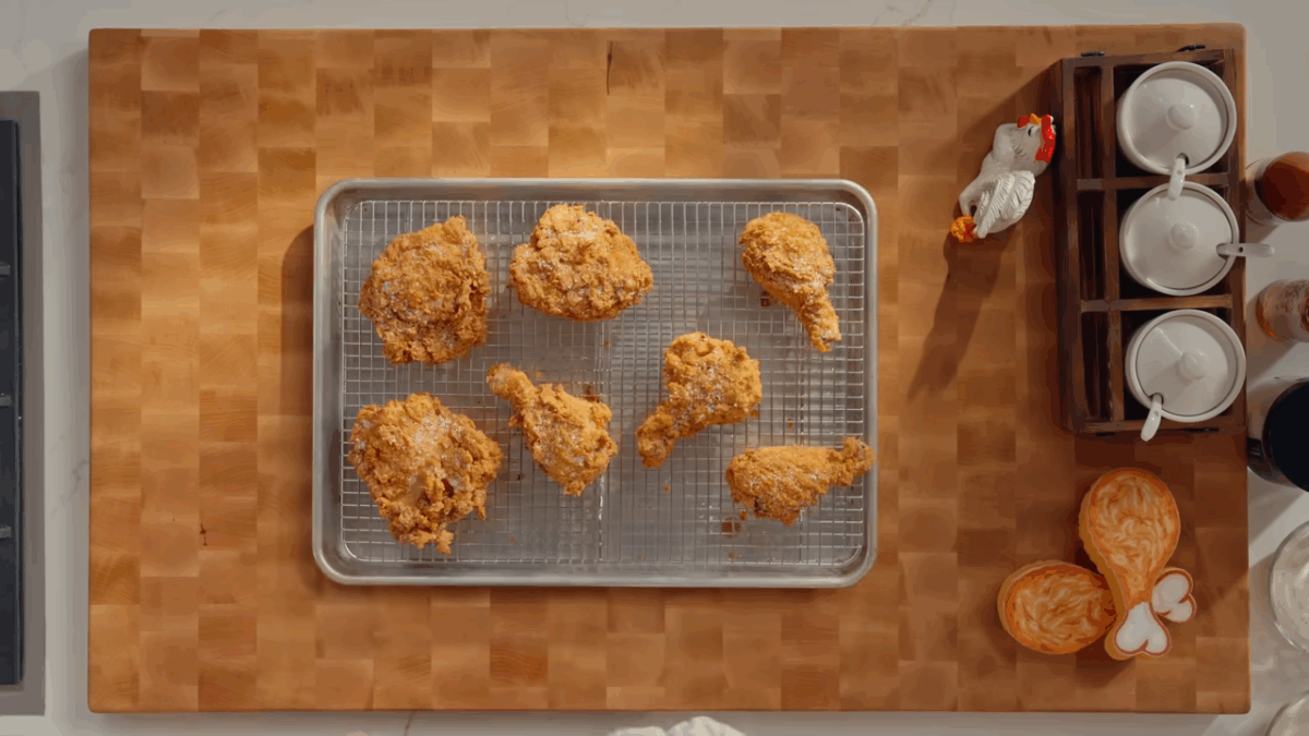 Fried chicken resting on a sheet tray lined with a wire rack.