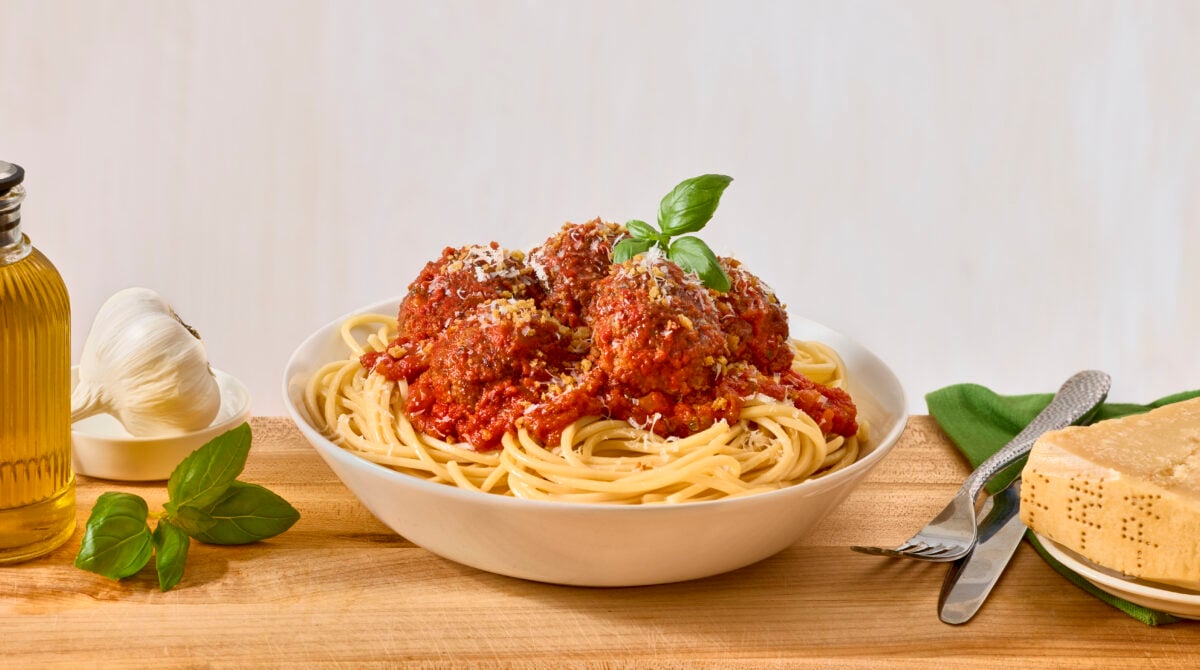 A bowl of spaghetti and meatballs topped with pangratto.
