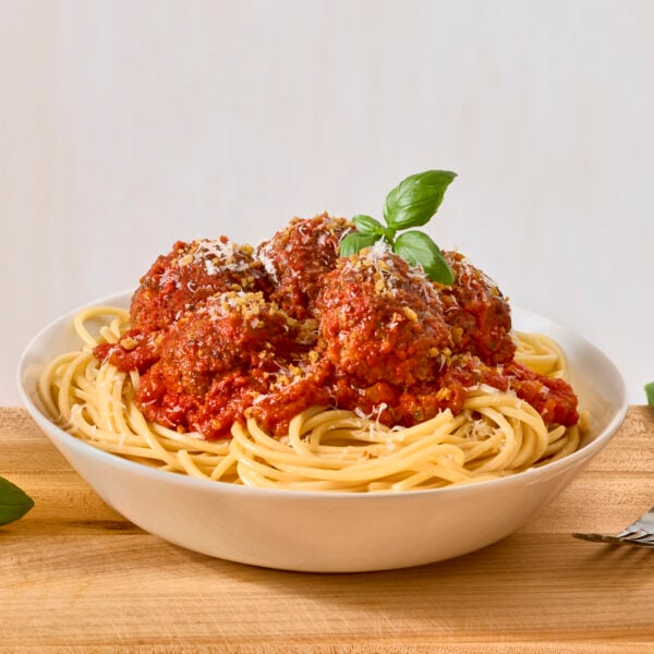 A bowl of spaghetti and meatballs topped with pangratto.