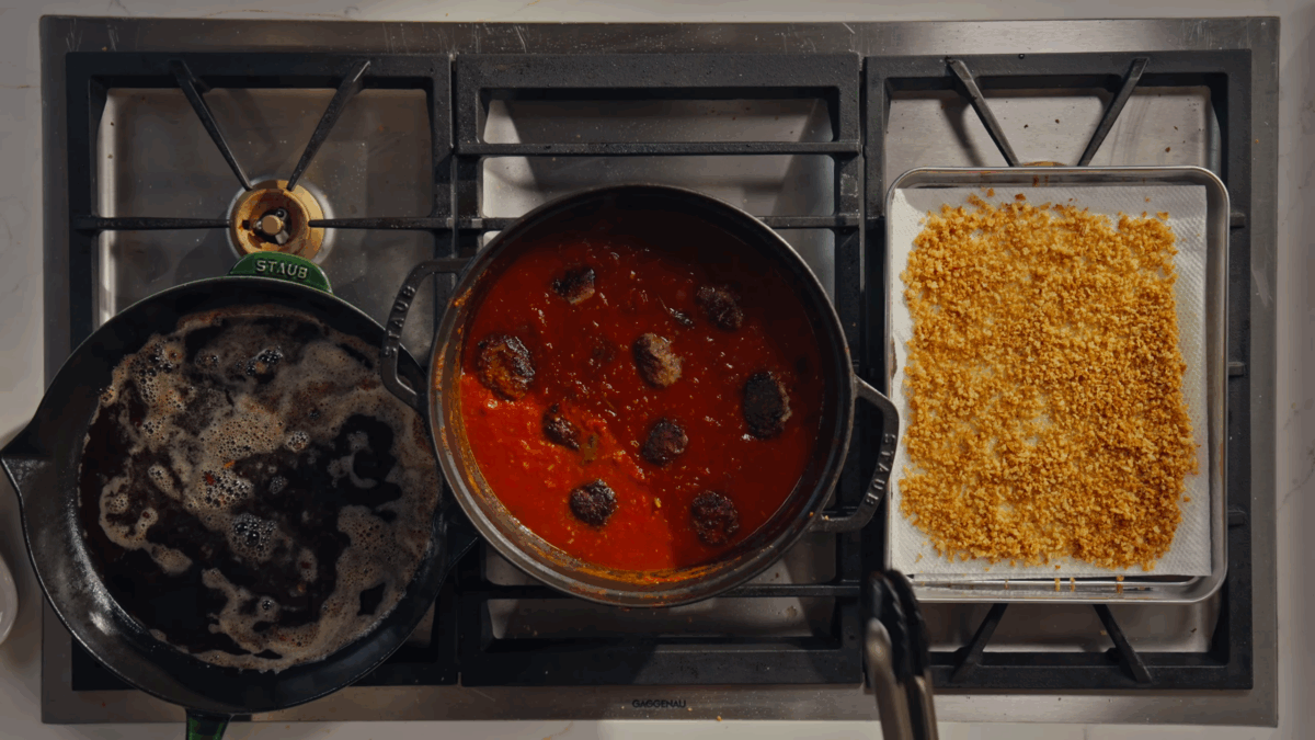 Meatballs simmering in tomato sauce in a Dutch oven.