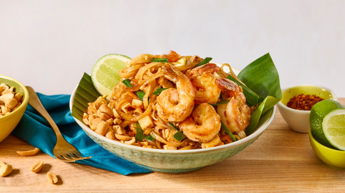 A bowl of shrimp pad Thai served with fresh lime.