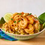 A bowl of shrimp pad Thai served with fresh lime.