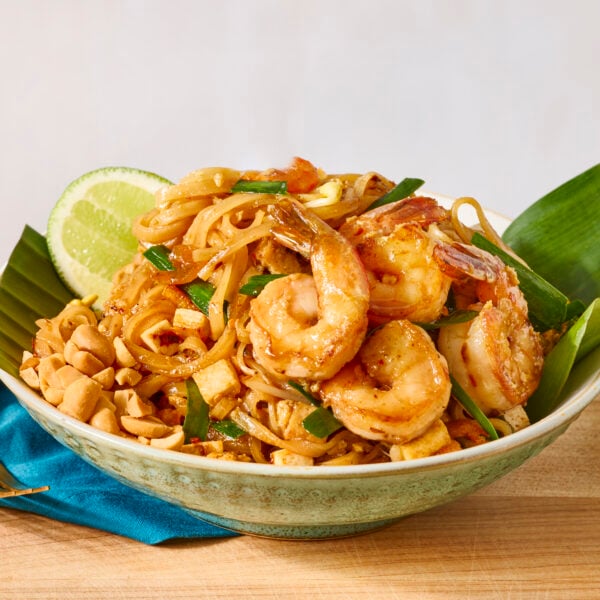 A bowl of shrimp pad Thai served with fresh lime.