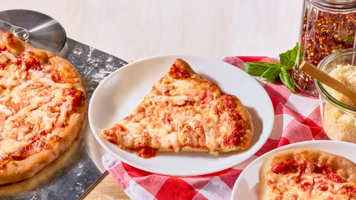 A slice of New York style pizza on a white plate.