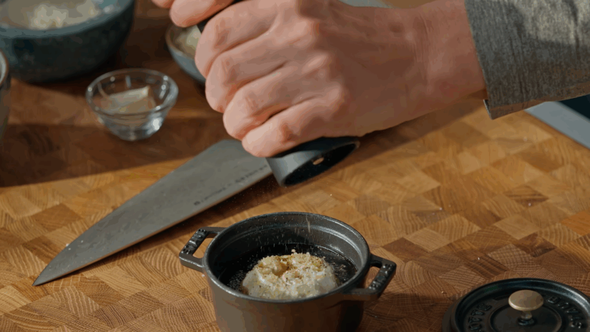 A whole head of garlic being seasoned to roast. 