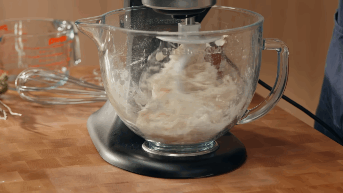 Pizza dough being combined in a stand mixer. 