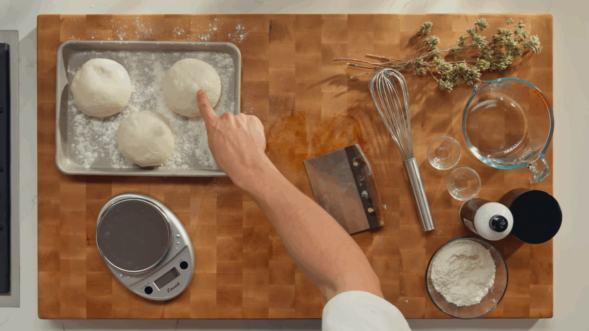 Three balls of dough on a  metal sheet tray. 
