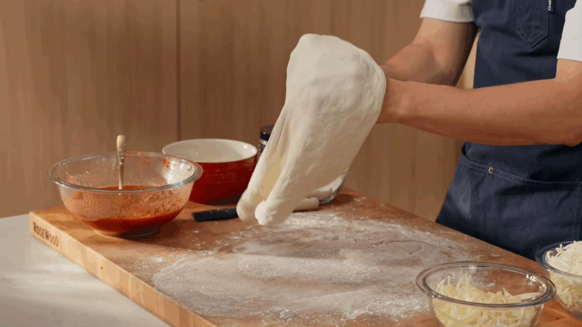 Pizza dough being stretched and shaped. 