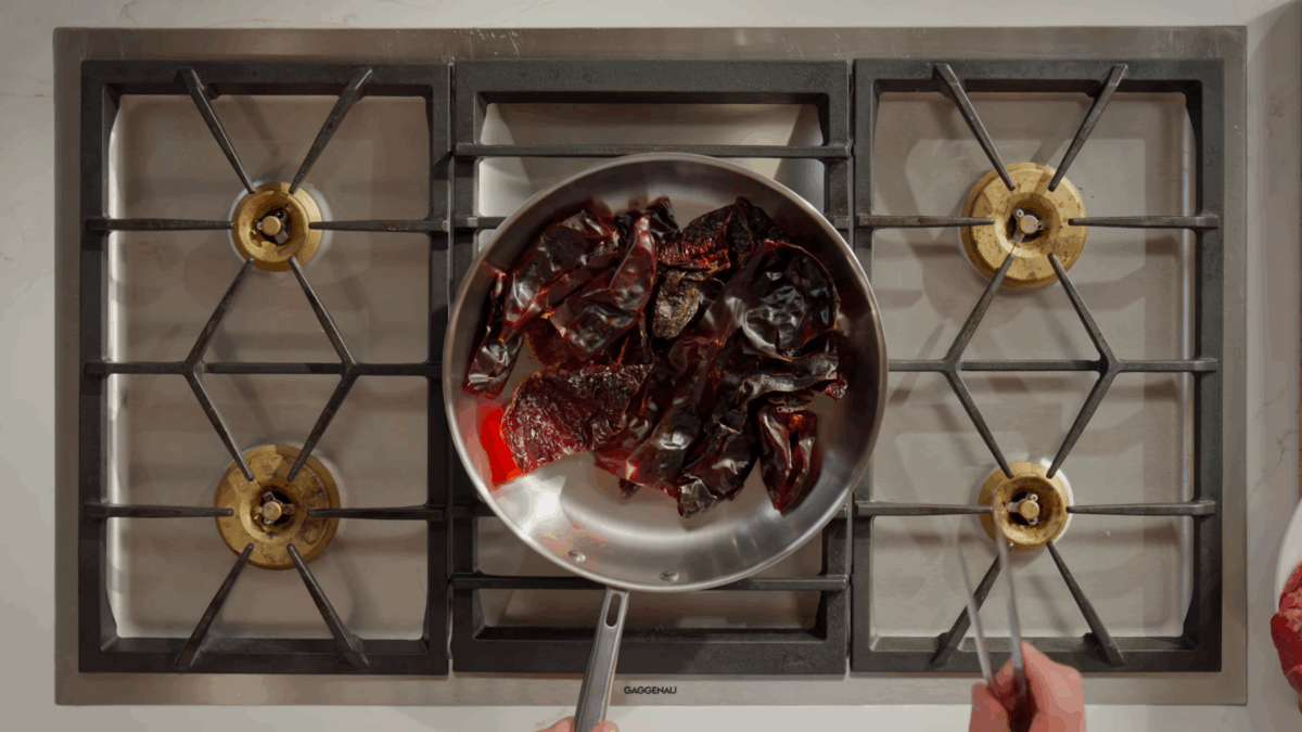 Chiles toasting in a skillet on the stove.