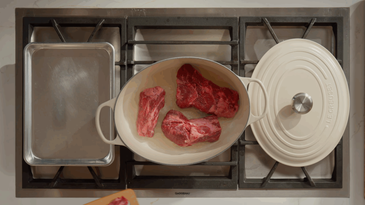Beef searing in a pan on the stove.