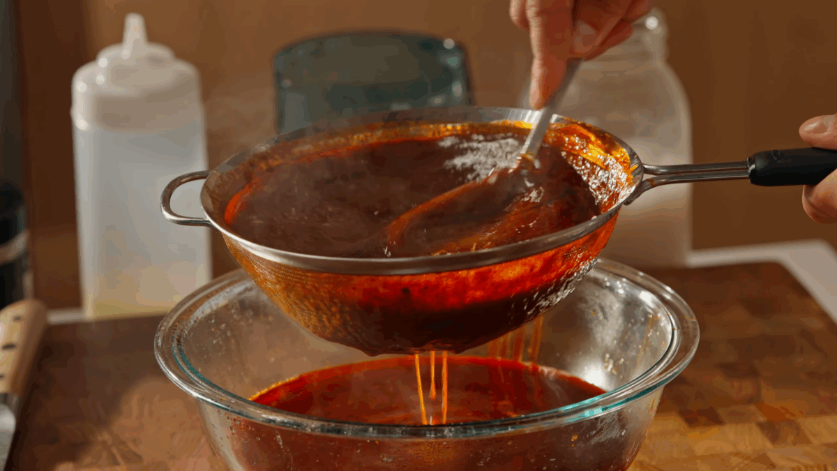 Consomé sauce being strained into a bowl.