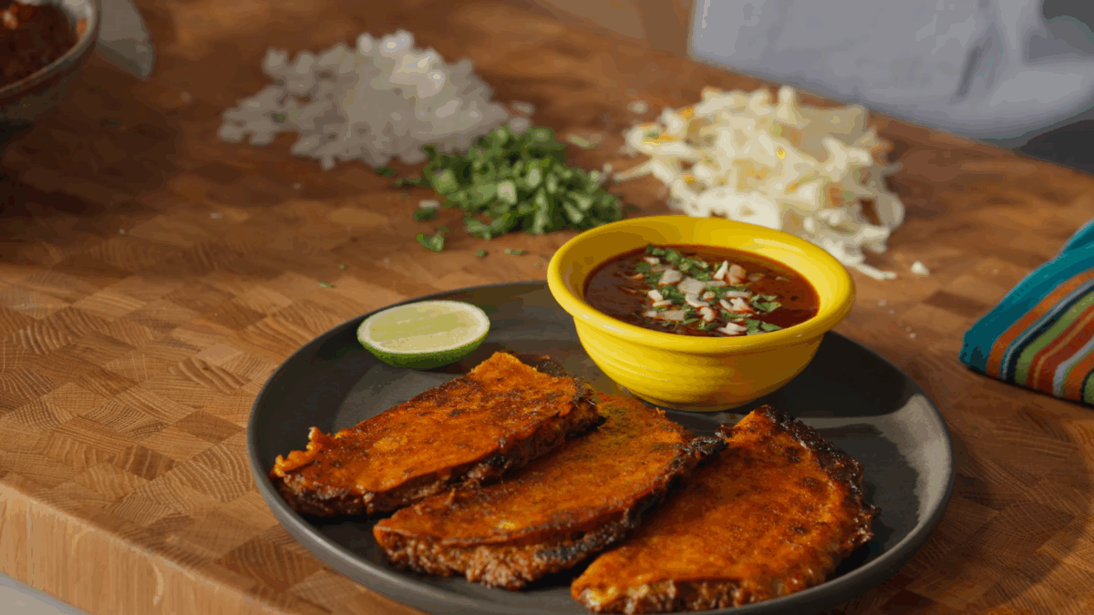 Three quesabirria tacos on a plate with a bowl of consomé sauce.