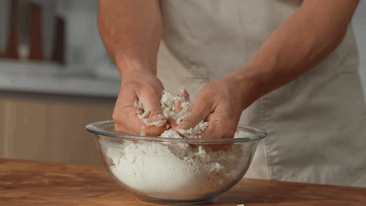 Tortilla dough being mixed in a bowl by hand. 