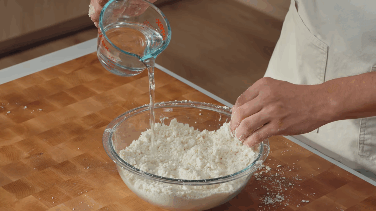 Water being poured into a bowl of tortilla dough. 