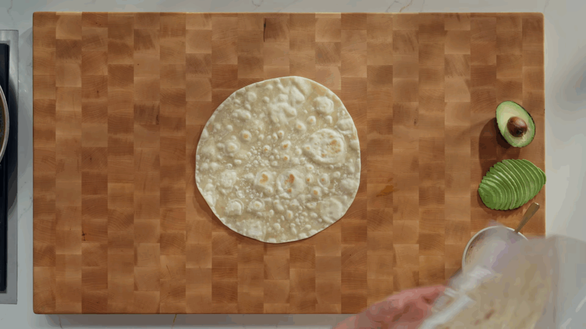 A homemade tortilla on a large wooden cutting board. 