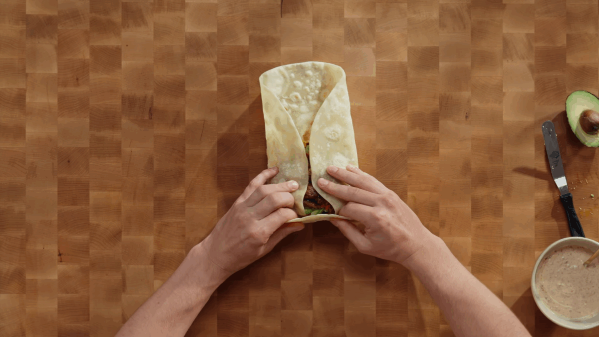 A breakfast burrito being rolled. 
