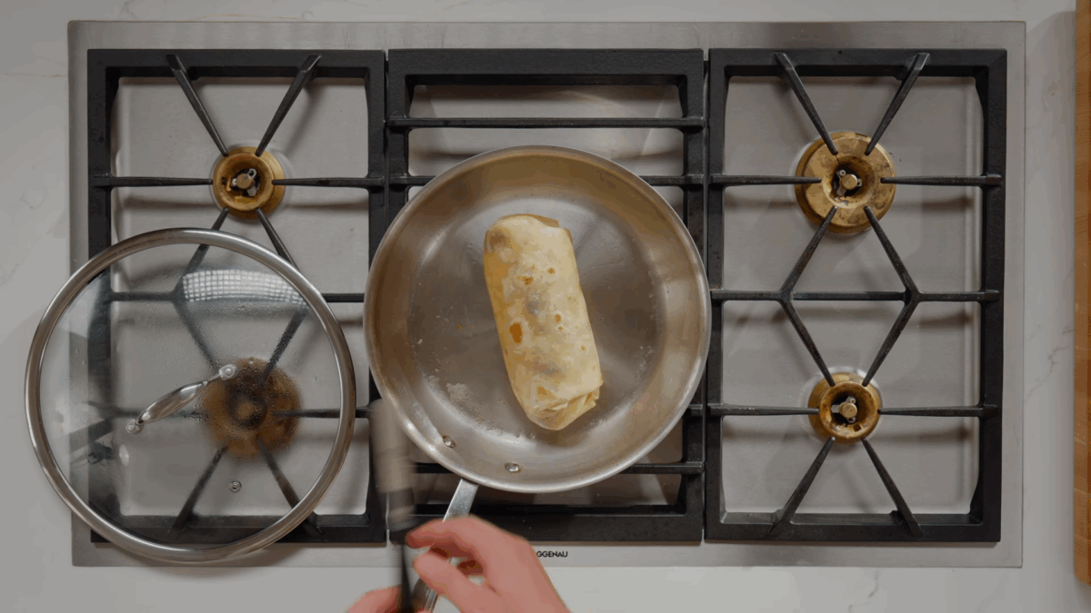 A toasted sausage breakfast burrito in a skillet. 