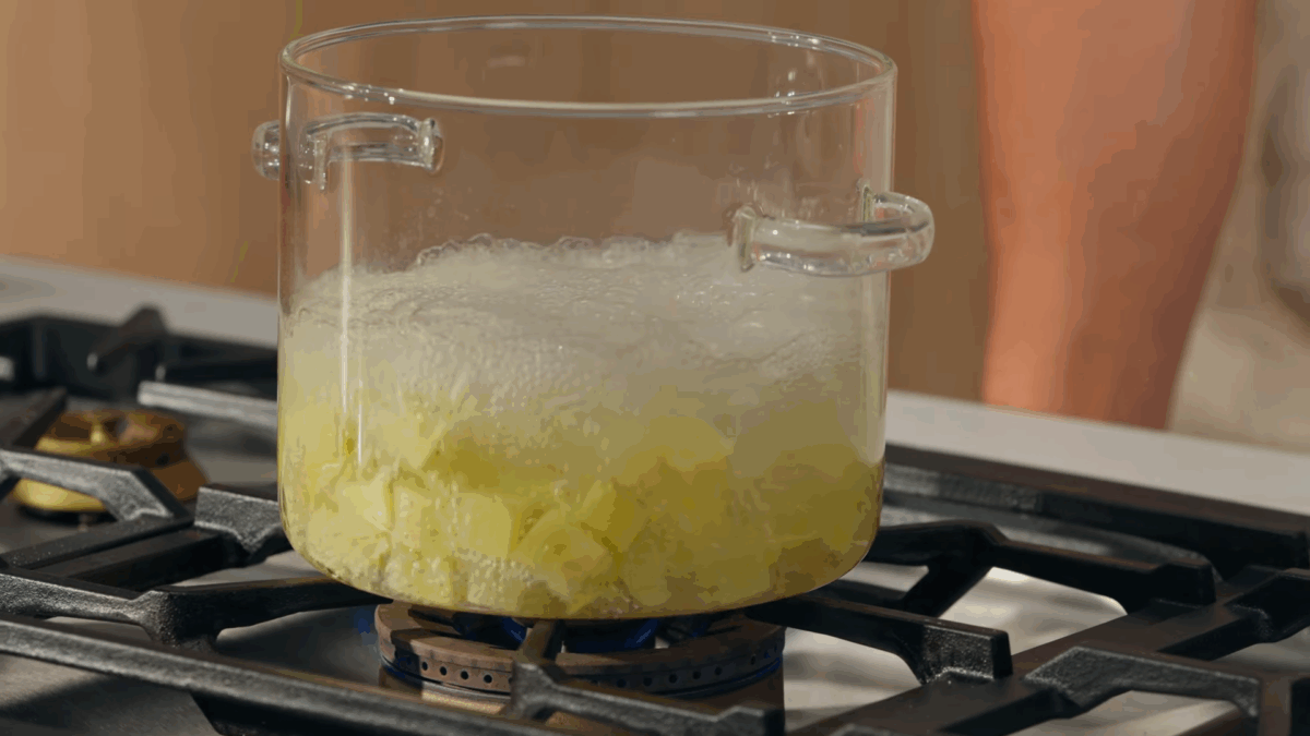 Potatoes boiling in a pot on the stove. 