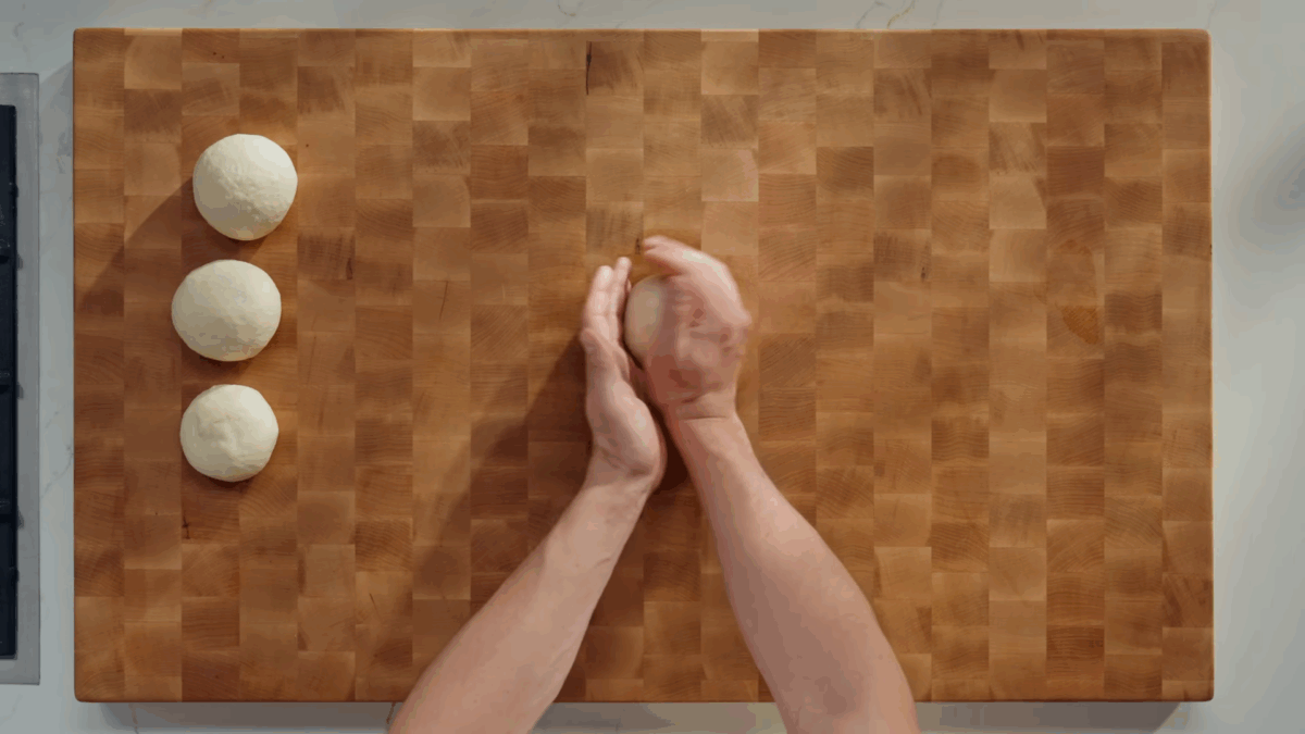 Four balls of tortilla dough being rolled and shaped. 