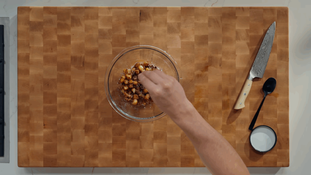 Home fries being seasoned in a bowl. 