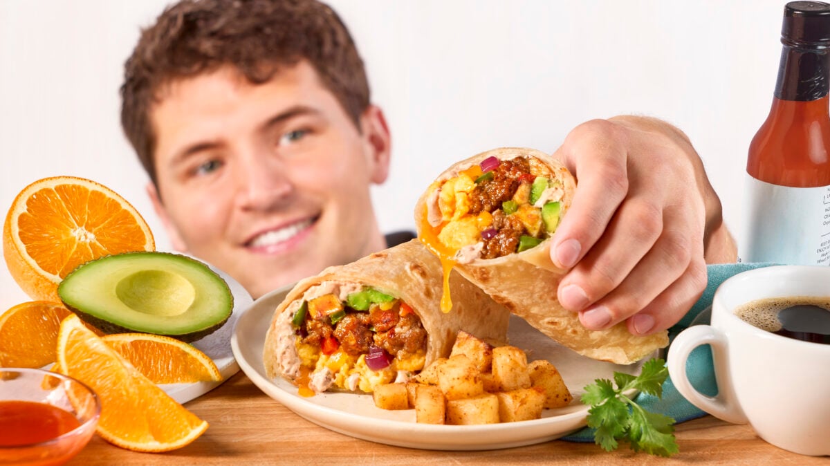 Nick DiGiovanni picking up a sausage breakfast burrito from a plate. 