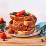 A stack of brioche French toast topped with fresh berries.