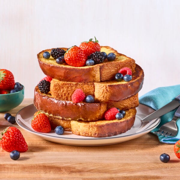 A stack of brioche French toast topped with fresh berries.