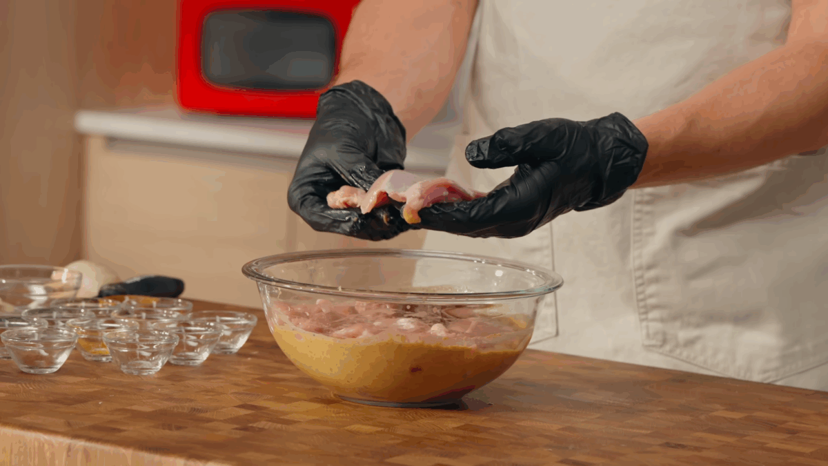 Raw chicken thighs being tossed in chicken shawarma marinade.