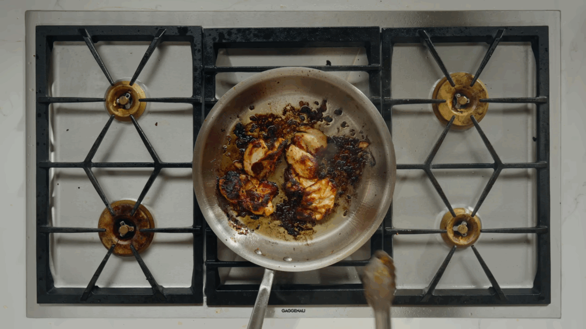 Chicken shawarma thighs cooking in a pan on the stove.