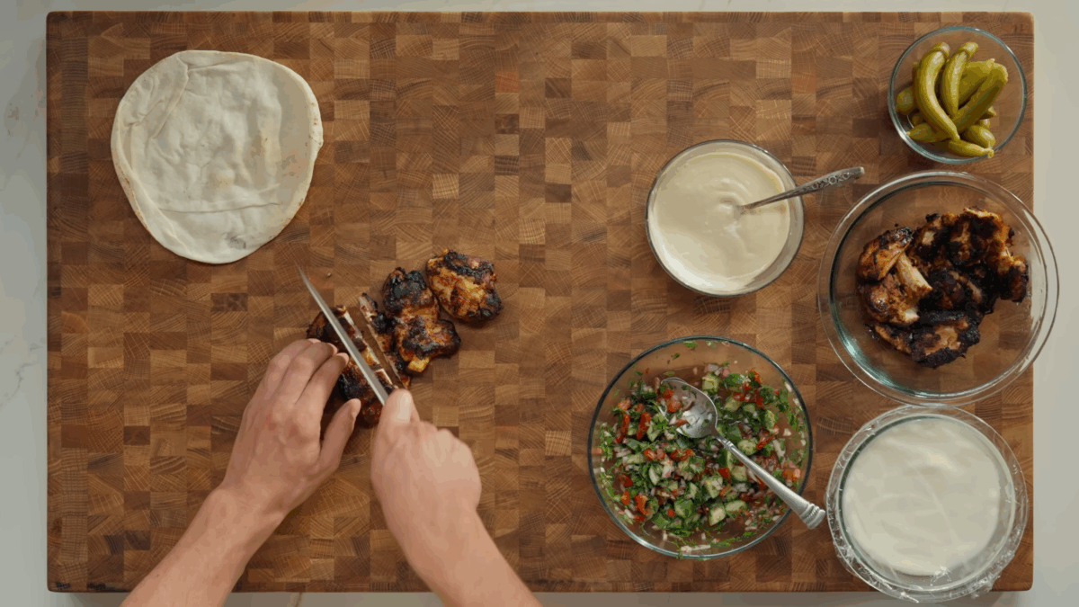 A chicken shawarma thigh being sliced on a cutting board.