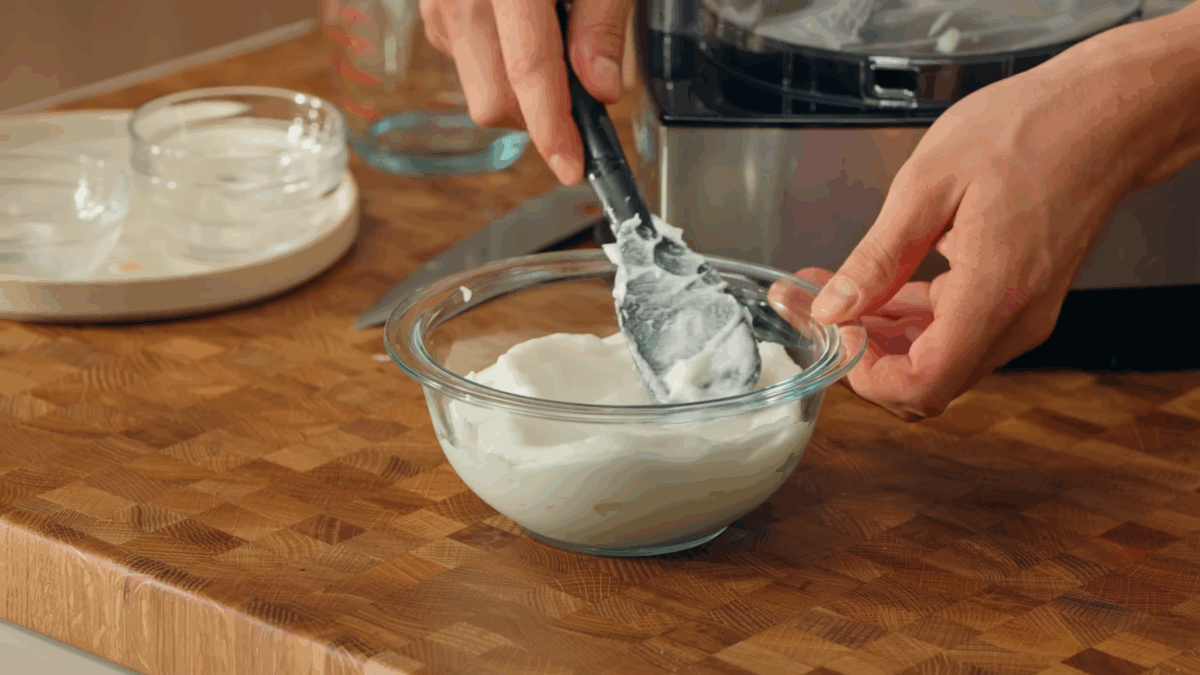 Toum sauce being transferred to a small glass bowl.