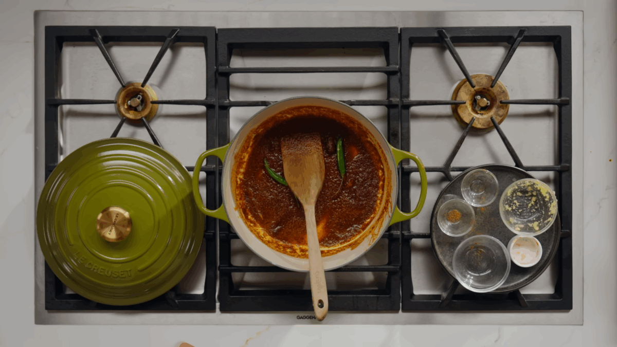 A pot of butter chicken sauce with green chiles on top.