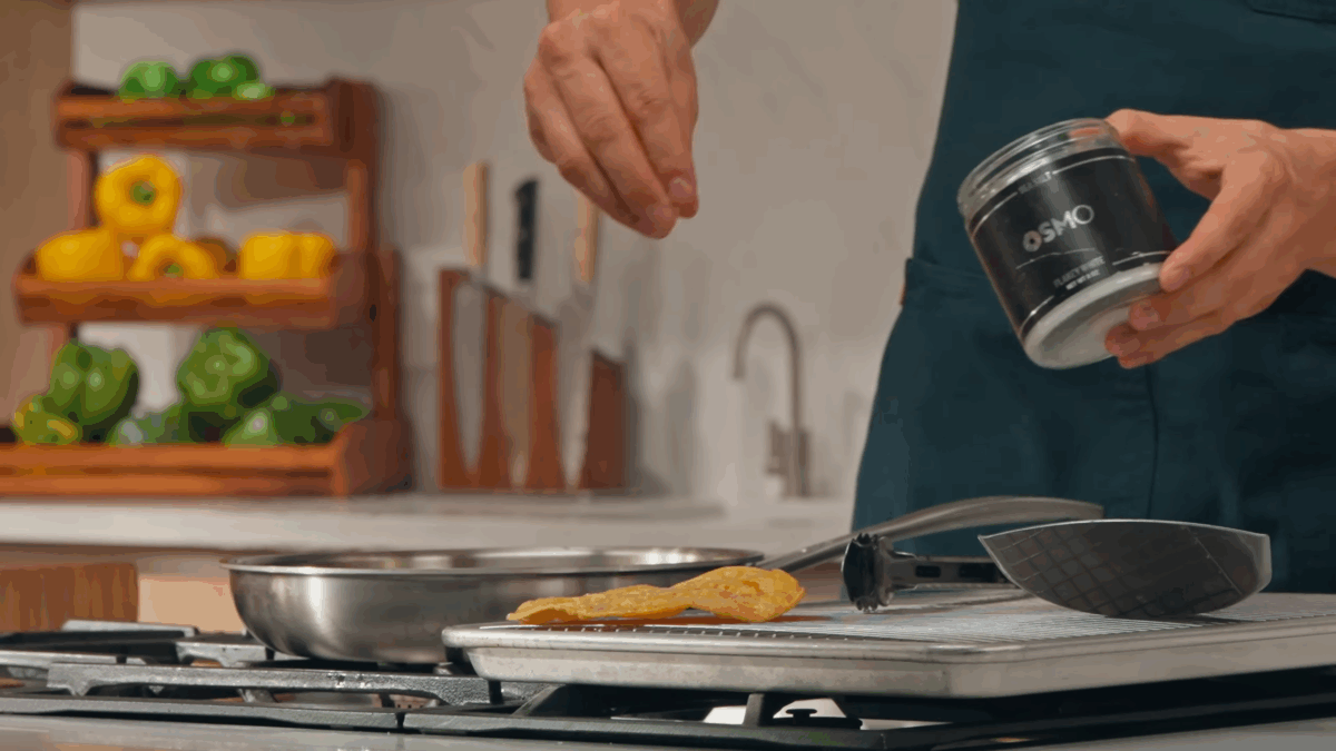 A fried tostada shell being seasoned with Osmo salt. 