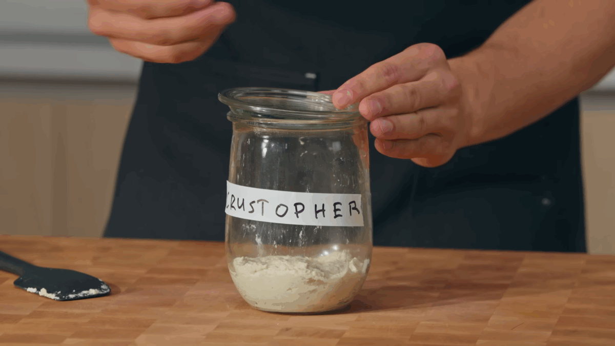 A jar of sourdough starter labeled Crustopher.
