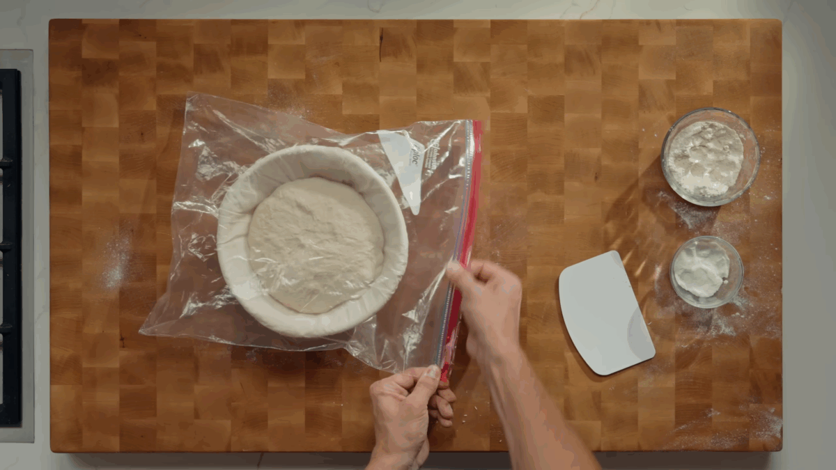 Nick DiGiovanni sealing a basket of sourdough bread dough in a plastic bag.
