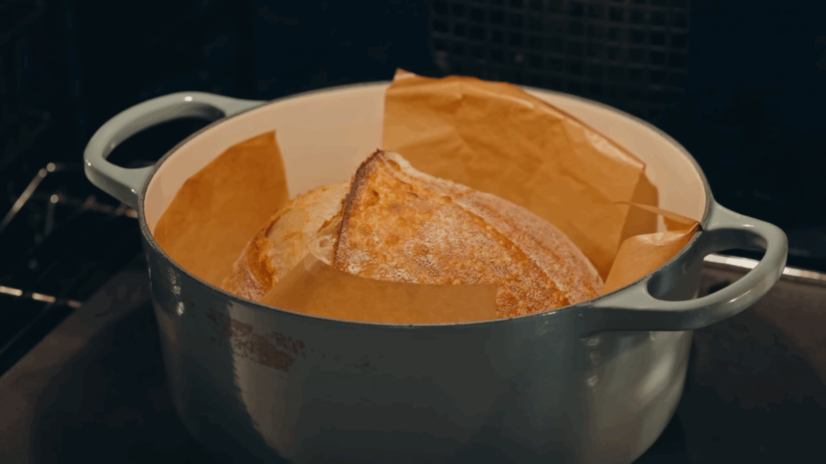 A sourdough bread loaf baking uncovered in an oven.