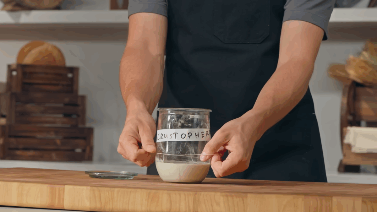Nick DiGiovanni placing a rubber band around a jar of sourdough starter.