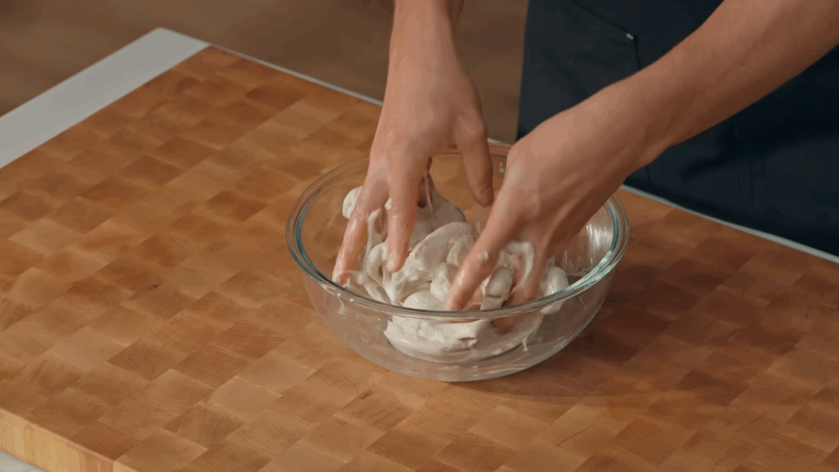 Nick DiGiovanni mixing sourdough bread dough with two hands.