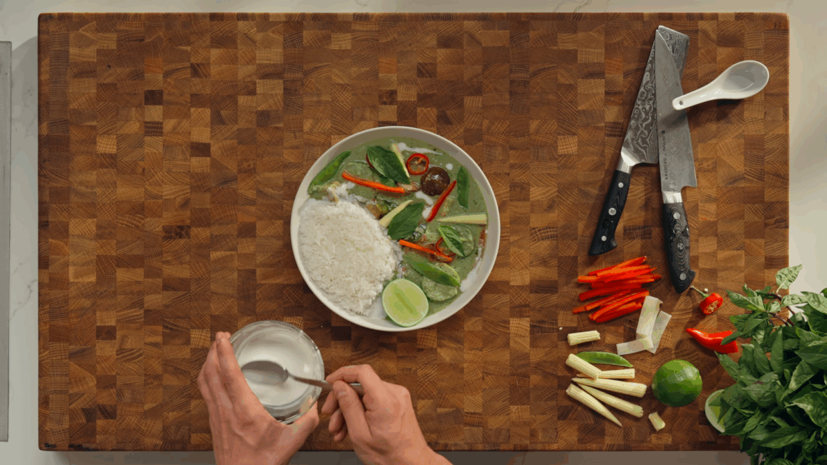 A plate of jasmine rice and Thai green curry with half a lime on the side.