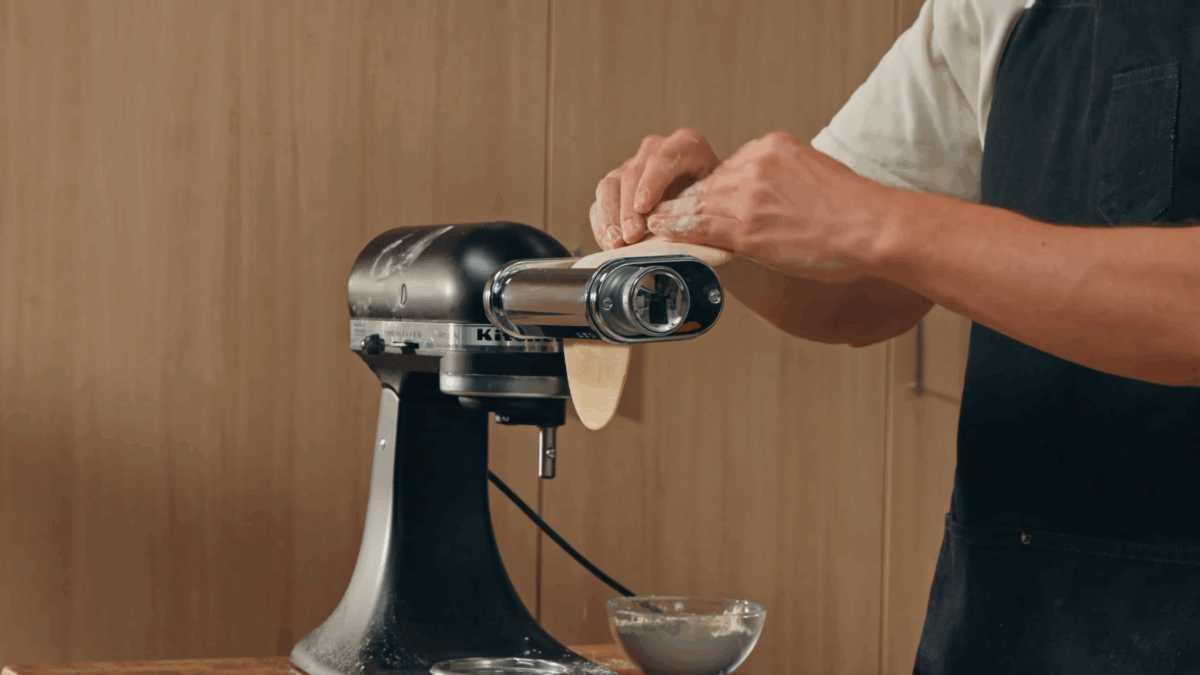 Nick DiGiovanni putting pasta dough through a stand mixer.