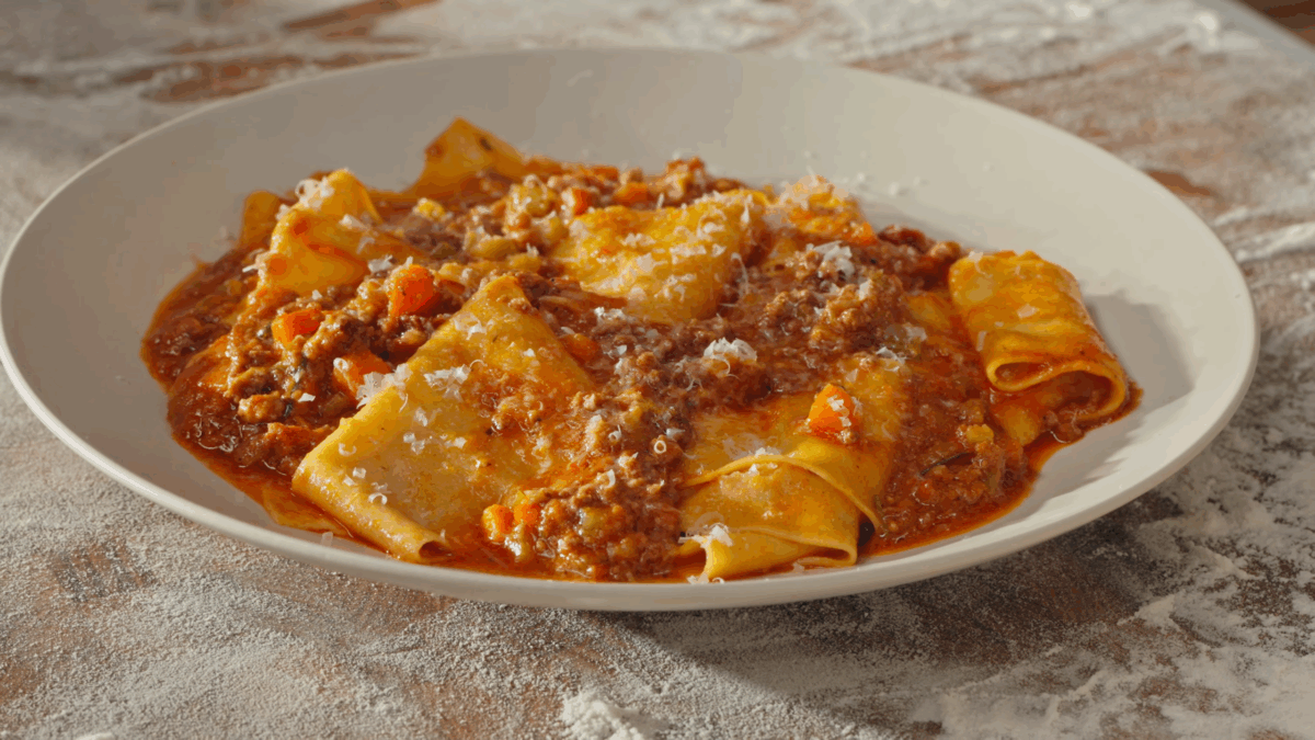 A plate of pasta bolognese topped with freshly grated Parmesan.