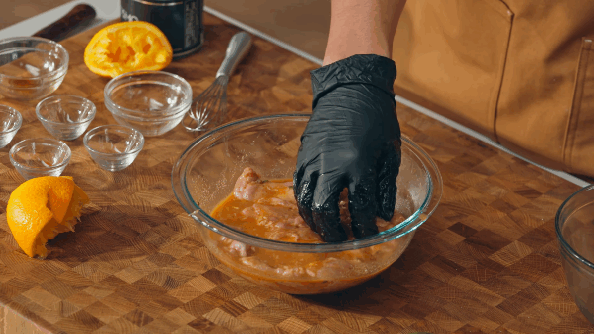 Nick DiGiovanni coating raw chicken thighs in a bowl of chipotle marinade.