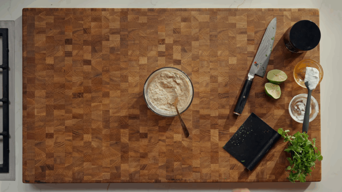 Creamy chipotle sauce in a bowl on a wooden cutting board.