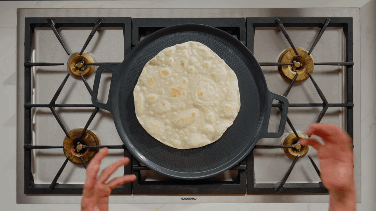 A homemade tortilla cooking on a stovetop.