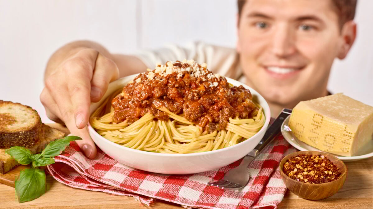 Nick DiGiovanni grabbing a bowl of spaghetti bolgonese from a table.