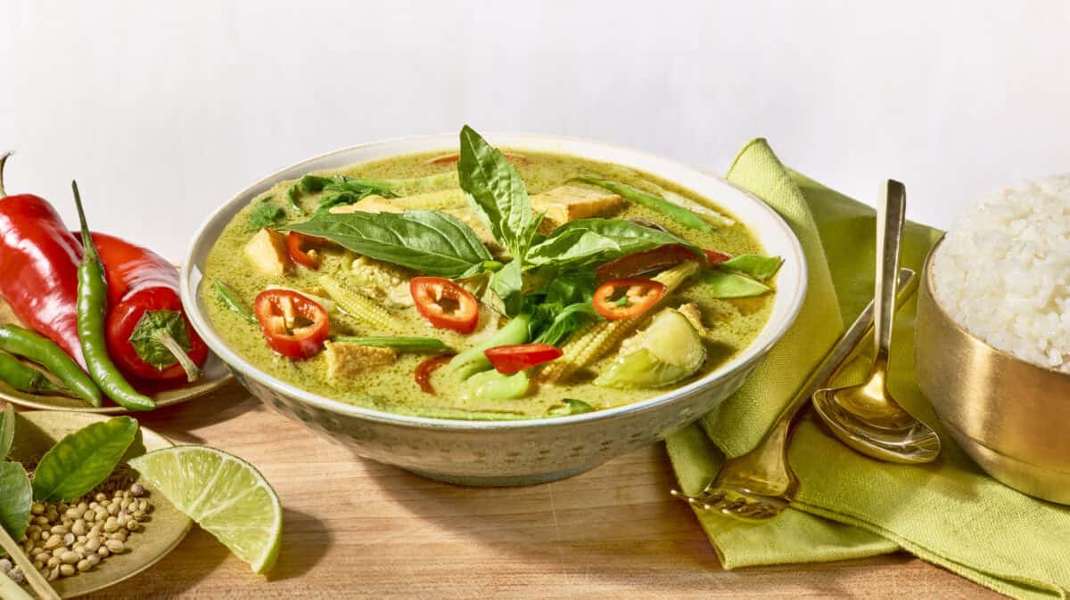 A bowl of Thai green curry topped with fresh herbs.