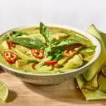 A bowl of Thai green curry topped with fresh herbs.