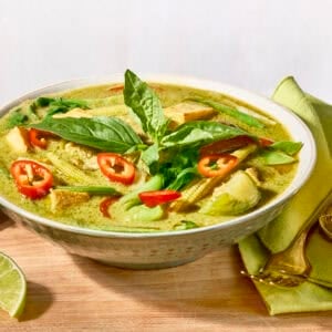 A bowl of Thai green curry topped with fresh herbs.